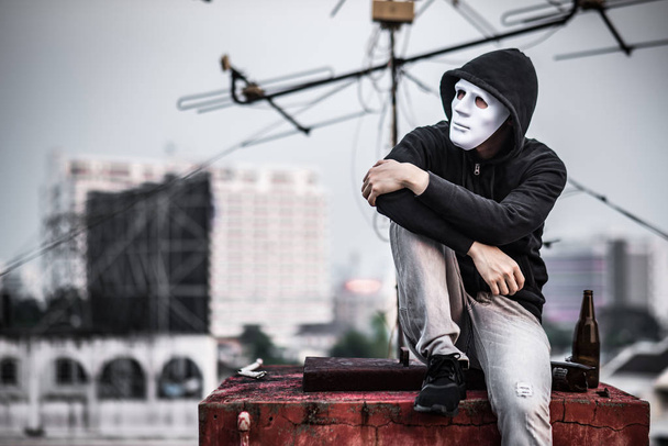Hombre misterioso en la máscara sentado con la botella vacía y rota
 - Foto, imagen