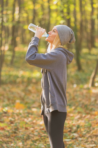 Sportvrouw drinkwater tijdens het joggen - Foto, afbeelding