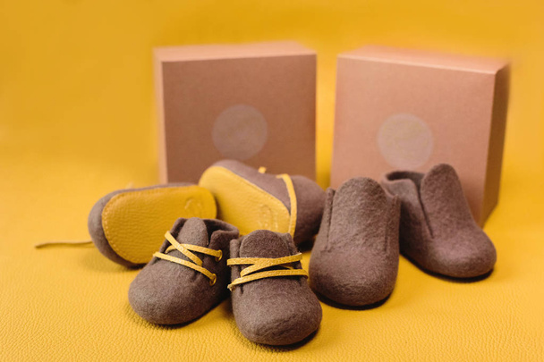 Brown, children's handmade shoes made of merino wool on a bright yellow background. - Photo, Image