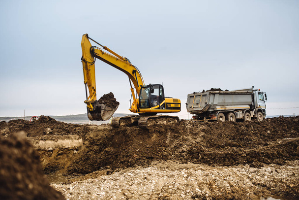 Máquinas industriais para serviços pesados, detalhes da construção de escavadeiras e caminhões basculantes no local de construção
 - Foto, Imagem