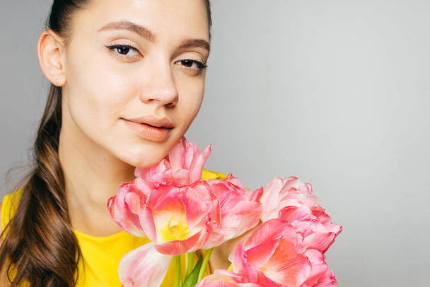 beautiful young girl enjoying the spring, holding a big bouquet of pink flowers - Fotó, kép