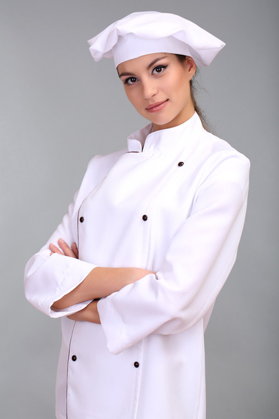 Portrait of young woman chef on grey background - Fotó, kép
