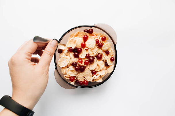 ciotola femminile con deliziosi cornflakes croccanti, pezzi di kiwi e mirtilli rossi su sfondo bianco, primo piano, colazione sana
  - Foto, immagini