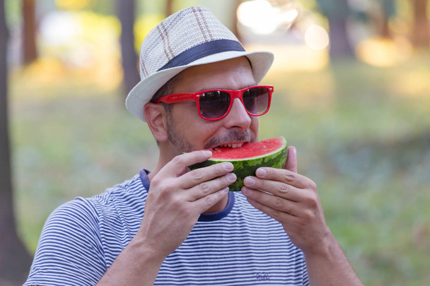 Hipster guy κρατά ένα κομμάτι καρπούζι και τρώτε - Φωτογραφία, εικόνα
