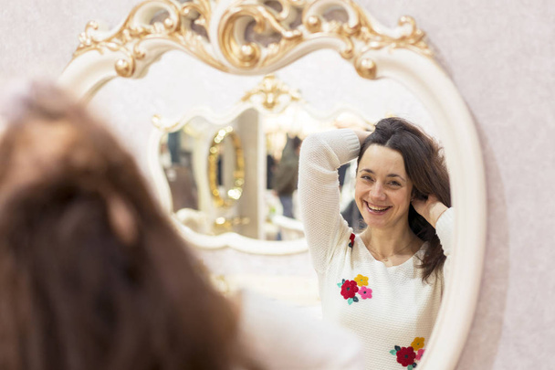 Jovem mulher na frente de um grande espelho
 - Foto, Imagem