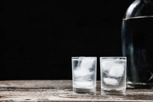 Cold vodka in shot glasses on a black background - Фото, зображення