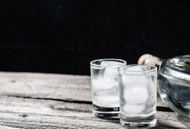 koude wodka in shot glazen op een zwarte achtergrond - Foto, afbeelding
