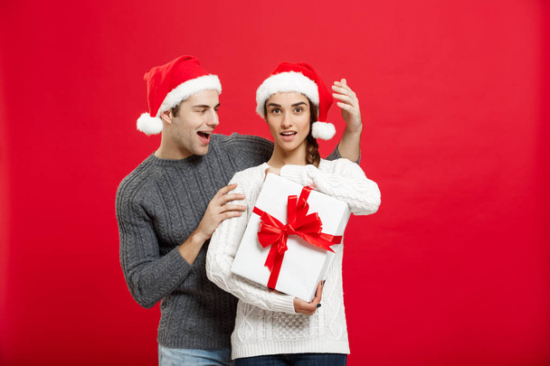 Concetto di Natale - bel ragazzo in maglione sorprende la sua ragazza con un regalo bianco
 - Foto, immagini
