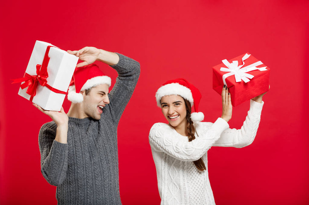 Concepto de Navidad - retrato de pareja joven en jersey de Navidad disfrutar jugando con regalos
 - Foto, imagen