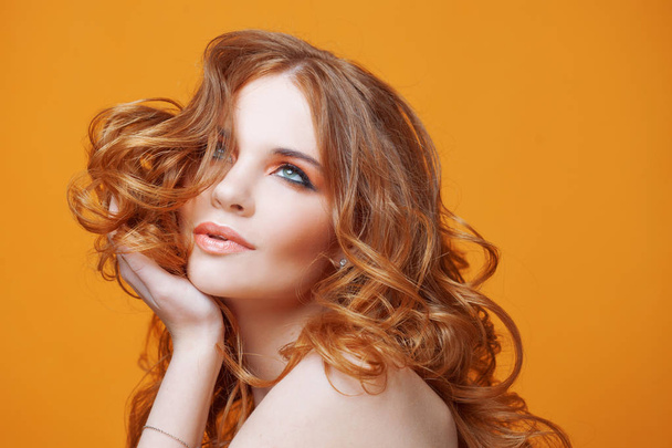 Beautiful redheaded girl with luxurious curly hair. Studio portrait on yellow background. Excellent hair - Foto, Bild