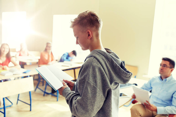 student boy with notebook and teacher at school - Φωτογραφία, εικόνα