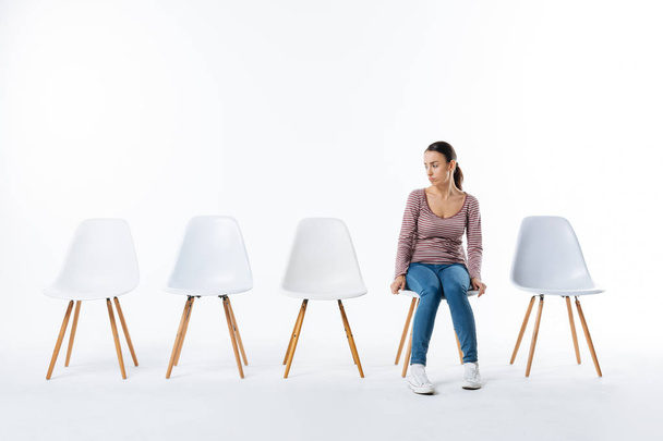 Serious young woman looking at empty chairs - Foto, Bild