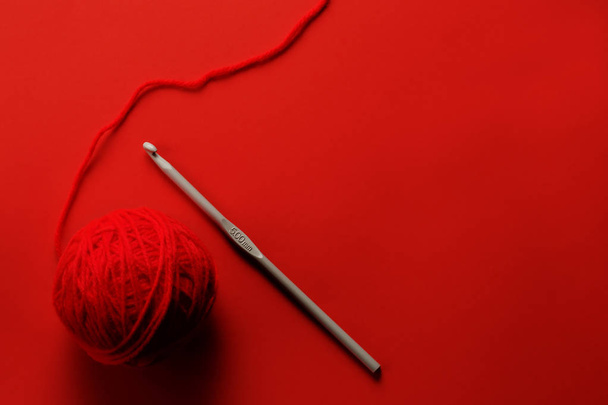Красная шерсть с вязаной иглой на фоне красной бумаги
 - Фото, изображение