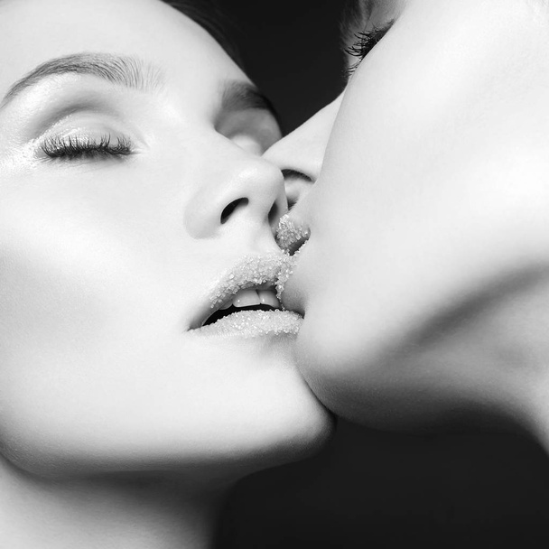 Kuss zweier Frauen mit Zucker auf den Lippen - Foto, Bild