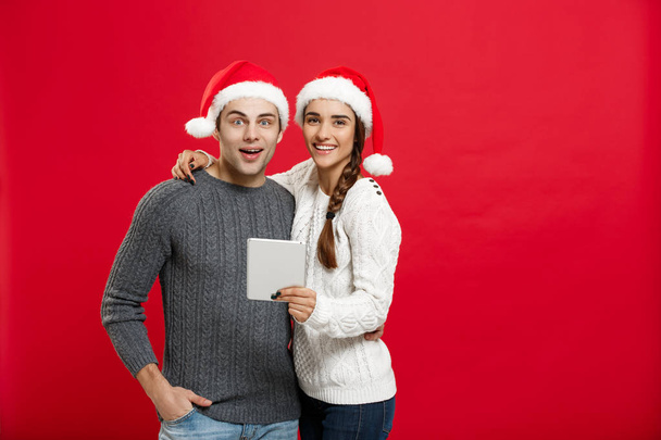 Weihnachtskonzept - junges hübsches und schönes Paar spielt am Weihnachtstag gerne auf dem Tablet - Foto, Bild