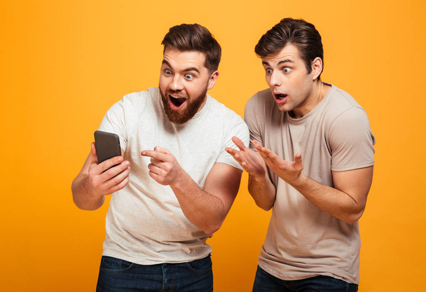 Image of two bachelors screaming and gesturing while watching ga - Fotografie, Obrázek