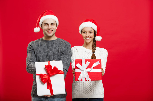 Christmas Concept - Young attractive couple giving gifts to each other celebrating in Christmas day - Photo, Image