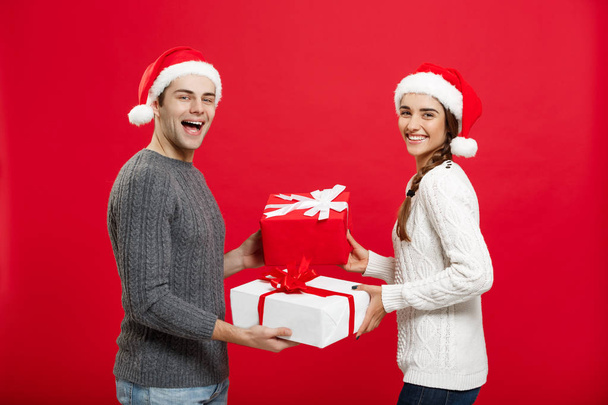 Christmas Concept - Young attractive couple giving gifts to each other celebrating in Christmas day - Foto, afbeelding
