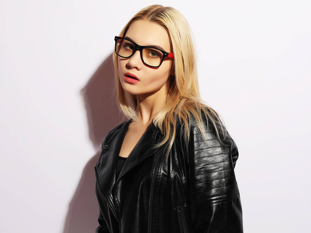 Fashion portrait of young blond woman. Black leather jacket, pants and glasses. - Photo, Image