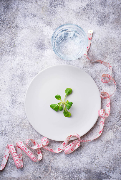 Plate with salad leaves, water and measuring tape - Foto, Bild