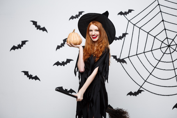 Retrato de bela bruxa caucasiana segurando abóbora para celebrar o Halloween
. - Foto, Imagem