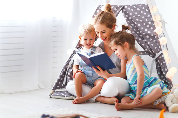 família mãe leitura para crianças livro na tenda em hom
 - Foto, Imagem