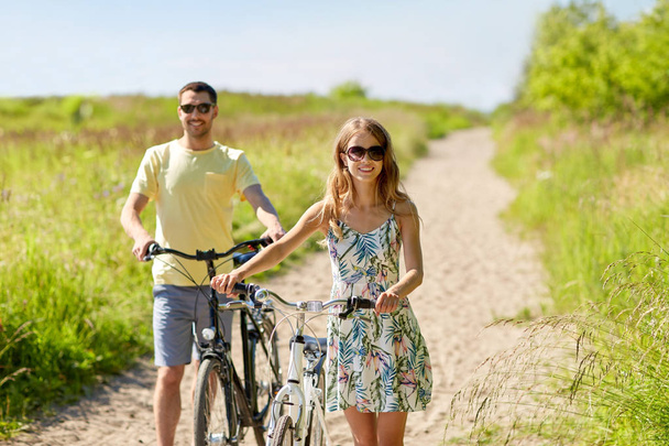 feliz pareja con bicicletas en el camino del campo
 - Foto, imagen