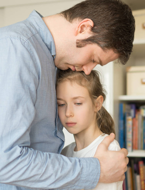 trauriges kleines Mädchen umarmt ihren Vater. - Foto, Bild