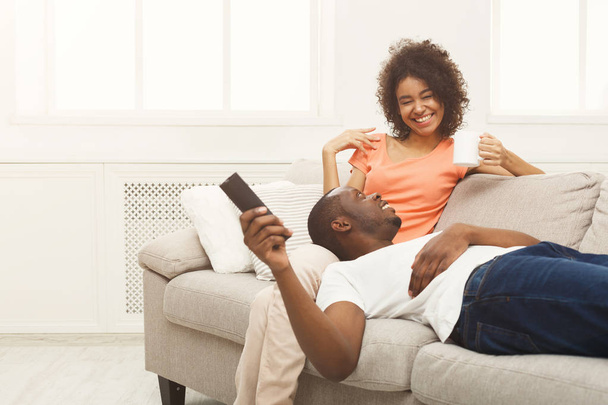 家でテレビを見て幸せなアフリカ系アメリカ人カップル - 写真・画像