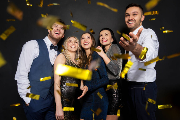 happy friends at party under confetti over black - Foto, Imagem