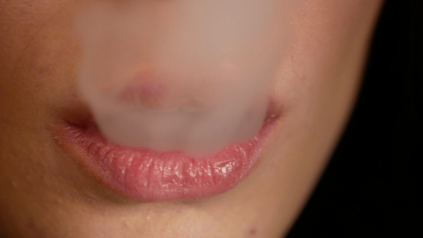 Primer plano de la mujer fumando. La chica libera lenta y sexualmente humo de un cigarrillo electrónico
 - Metraje, vídeo