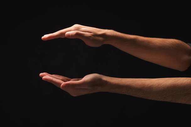 Male hands measuring something on black background - Photo, Image