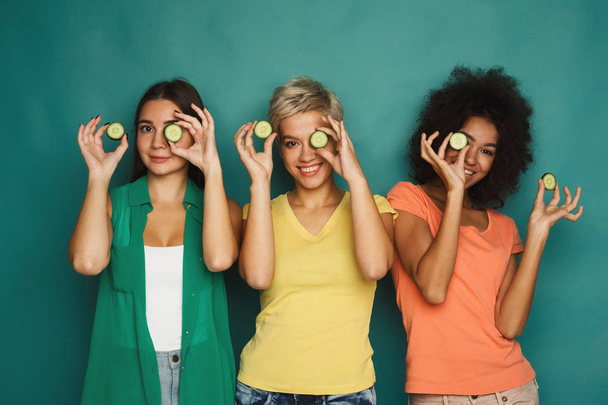Three beautiful girls covering eyes with cucumber pieces - Photo, Image