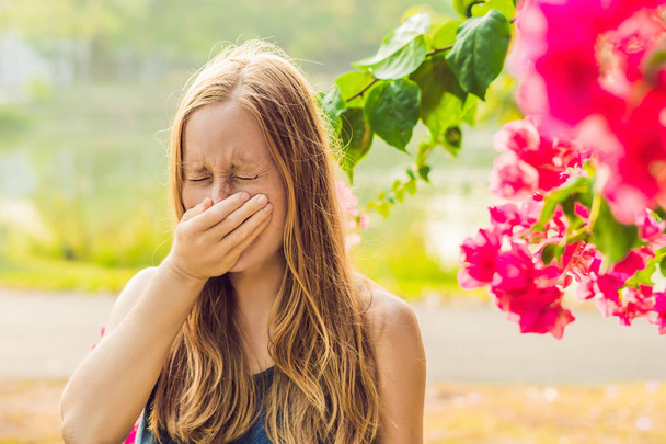 Pollen allergy concept. Young woman is going to sneeze. Flowering trees in background. - Φωτογραφία, εικόνα