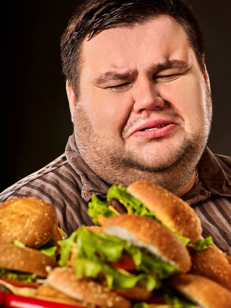 Fat man eating fast food hamberger. Breakfast for overweight person. - Foto, imagen