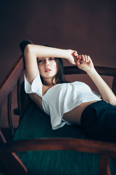 young woman relaxing on sofa, hands bent behind head - Foto, imagen