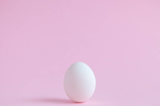 White egg isolated on pale rose background. - Foto, afbeelding