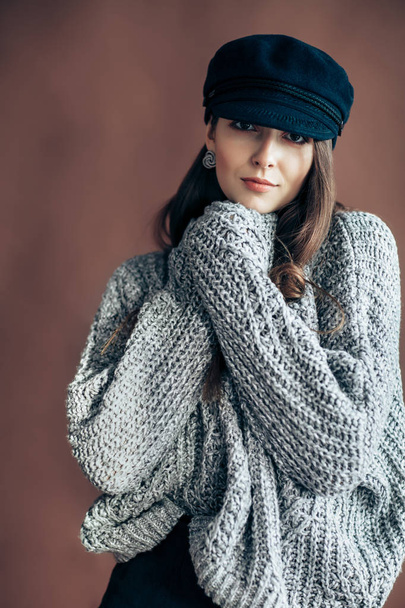 Fashion portrait of young woman in wool sweater on brown background - 写真・画像