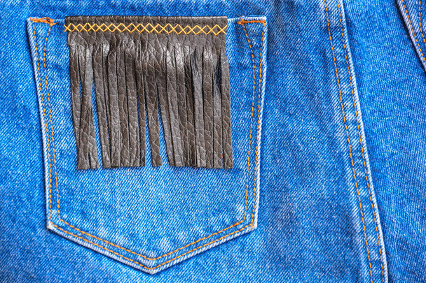 Фрагмент джинсовых брюк с карманом, украшенным кожей
  - Фото, изображение