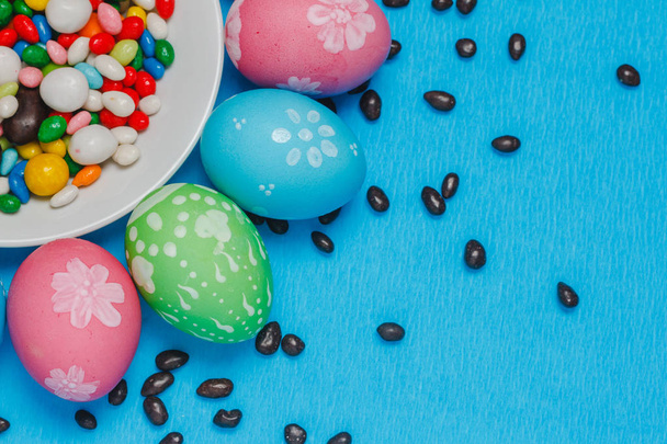 colored easter eggs on a saucer on a blue background - Фото, изображение