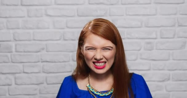 Expresiones faciales de mujer pelirroja joven en la pared de ladrillo
 - Metraje, vídeo