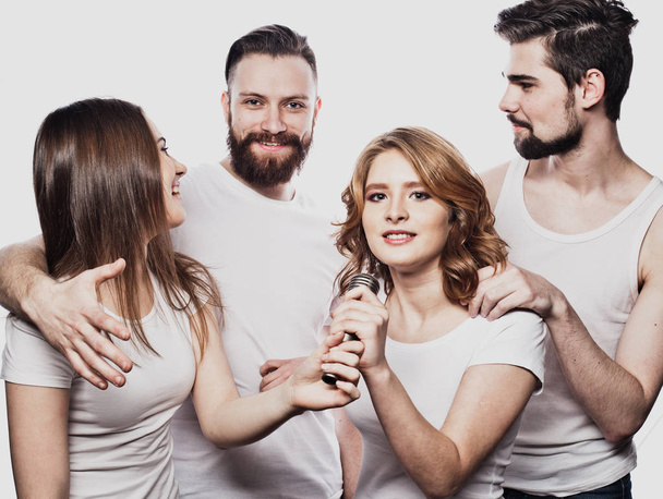 Group of friends playing karaoke over white background. Concept about friendship and people. - Fotó, kép