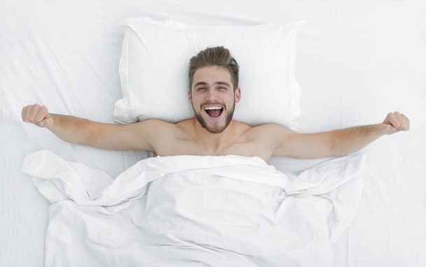 top view. happy man waking up in a comfortable bed - Fotoğraf, Görsel