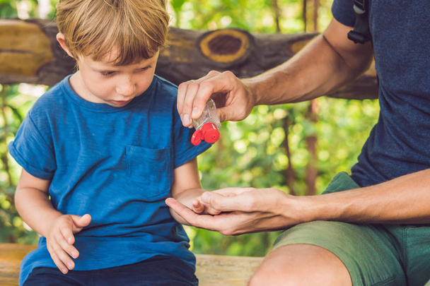 Father and son using wash hand sanitizer gel in the park before a snack. - 写真・画像