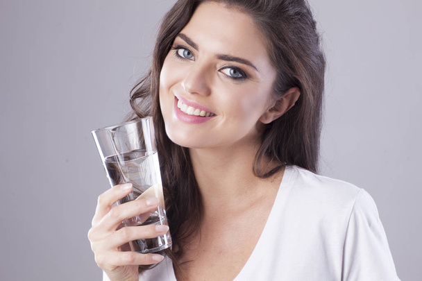 Молода жінка з прекрасною посмішкою п'є воду
. - Фото, зображення