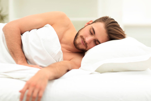 smiling man sleeping on a comfortable bed. - 写真・画像
