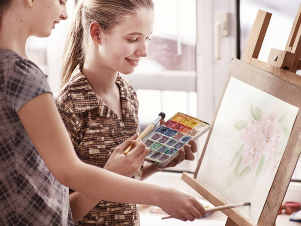 Artist painting on easel in studio. Authentic children paints . - Foto, imagen