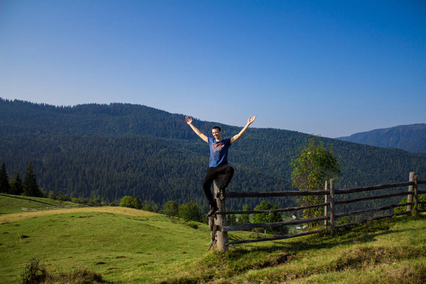Man met handen omhoog bovenop bergen met blauwe lucht. Man genieten van gratis geluk in het mooie landschap. Travel concept - Foto, afbeelding