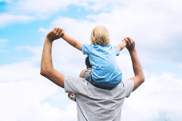 Father and son with raised arms up against the sky.   - Zdjęcie, obraz