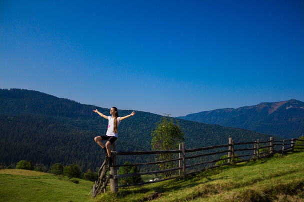 Vrouw met handen omhoog bovenop bergen met blauwe lucht. Vrouw genieten van gratis geluk in het mooie landschap. Travel concept - Foto, afbeelding